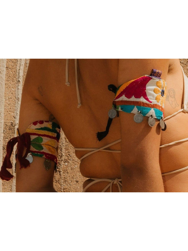 Añade un toque de tradición y originalidad a tus creaciones con estas piezas únicas inspiradas en el arte tribal Banjara. Se trata de retales bordados a mano, adornados con monedas colgantes que aportan movimiento y un carácter distintivo. Gracias a sus cintas en los extremos, puedes ajustarlas donde desees: botas, muñecas, bolsos o incluso customizar prendas con un aire bohemio y auténtico. Cada pieza es única, reflejando la riqueza cultural de las tribus nómadas de la India.