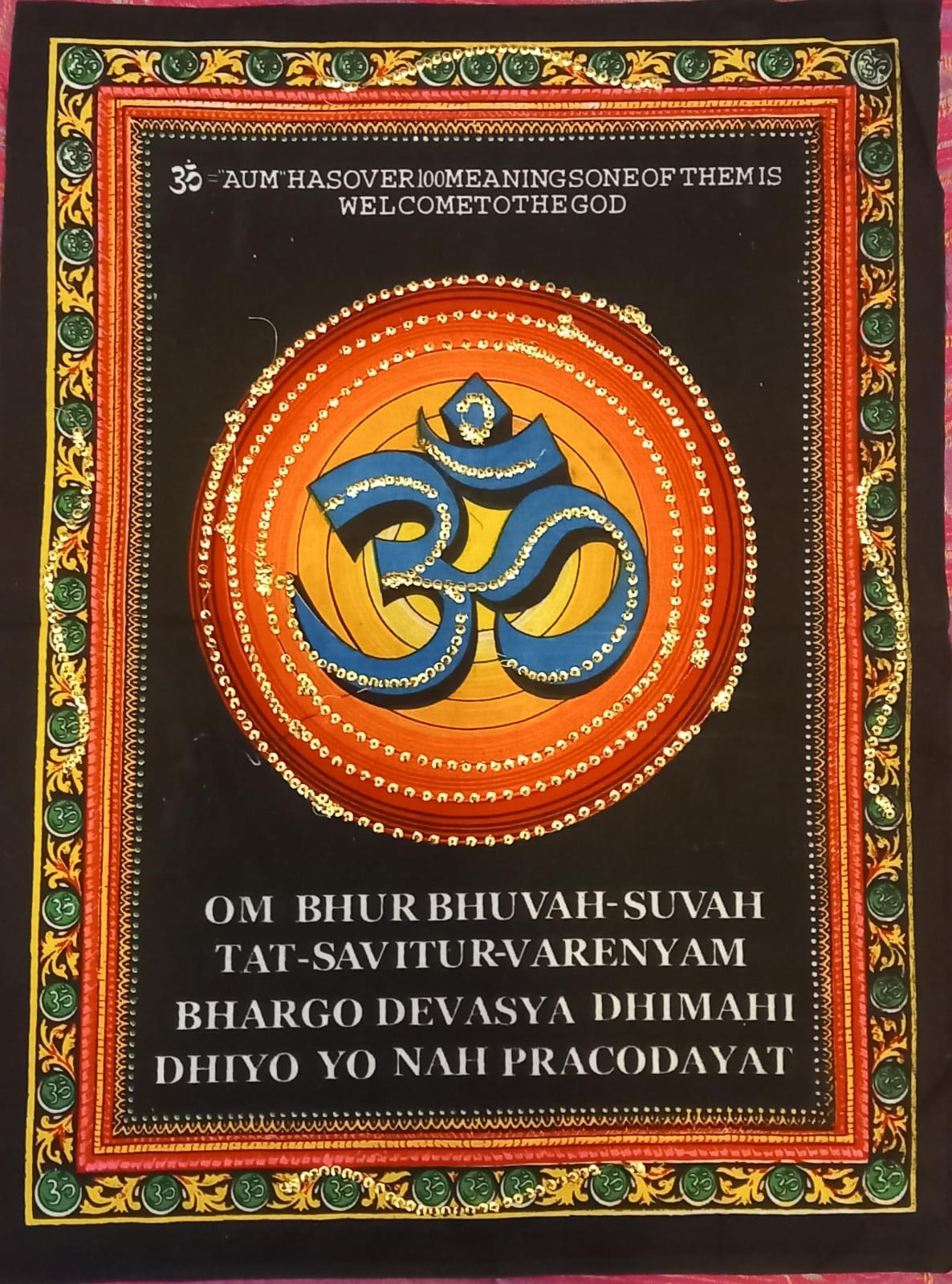 homenaje textil a la espiritualidad y la tradición hindú. El tapiz OM de 40x58 cm está elaborado con tela estampada y adornado con vibrantes colores y lentejuelas que aportan luz y profundidad. Sobre un fondo negro destacan símbolos y mantras sagrados como el OM. El OM es el mantra principal y más sagrado en las religiones dhármicas (hinduismo y budismo entre ellas) y representa la vibración máxima, el origen de todos los demás sonidos.Mediante su pronunciación podemos entrar en contacto con lo más profund