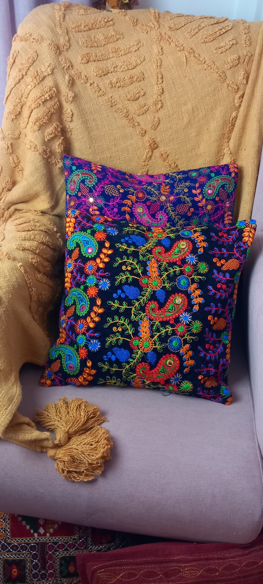 Un toque bohemio y artesanal para cualquier espacio. Esta funda de cojín Old Banjara es una pieza única, confeccionada con retales de tejidos tradicionales llenos de historia. Sus vibrantes bordados, detalles en espejos y abalorios la convierten en un complemento perfecto para quienes buscan decorar con personalidad y autenticidad. Su apertura trasera facilita la colocación del relleno, aportando comodidad y practicidad.