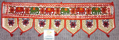 Un detalle que transforma cualquier espacio con esencia étnica y espiritual. El Torán Gora de 30x100 cm es una pieza elaborada artesanalmente en algodón con fondo color hueso, decorada con bordados coloridos y pequeños espejos que capturan la luz. Tradicionalmente usado en India para decorar puertas como símbolo de bienvenida y protección, hoy es ideal para paredes, escaparates, mostradores o como toque original en stands de mercado. Cada unidad es única, con composiciones distintas que harán que tu ambient