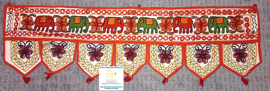 Un detalle que transforma cualquier espacio con esencia étnica y espiritual. El Torán Gora de 30x100 cm es una pieza elaborada artesanalmente en algodón con fondo color hueso, decorada con bordados coloridos y pequeños espejos que capturan la luz. Tradicionalmente usado en India para decorar puertas como símbolo de bienvenida y protección, hoy es ideal para paredes, escaparates, mostradores o como toque original en stands de mercado. Cada unidad es única, con composiciones distintas que harán que tu ambient