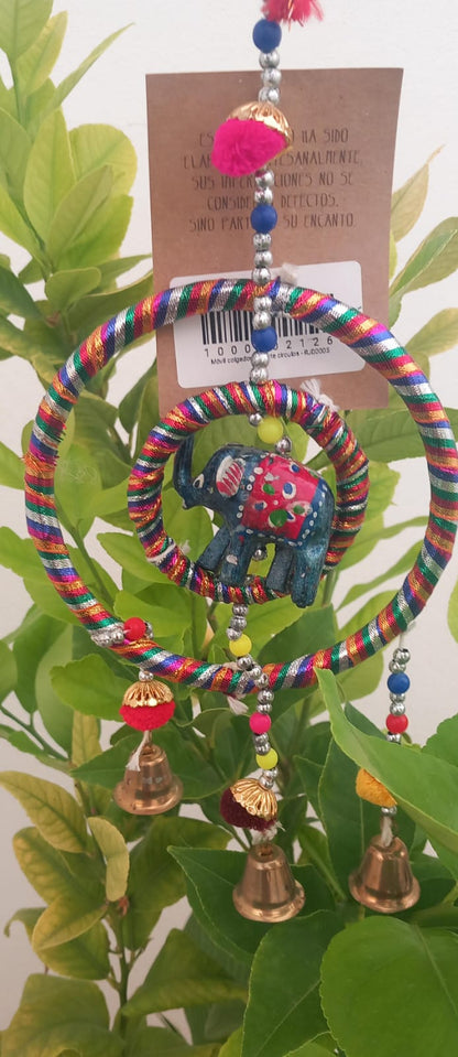 Un colgador encantador que combina tradición y ternura. Este móvil decorativo está elaborado artesanalmente con tela y presenta una estructura circular de la que cuelgan campanas metálicas que producen un suave sonido al moverse con el aire. En su centro, un elefante de la suerte aporta un toque simbólico y alegre. Perfecto para decorar habitaciones infantiles, escaparates o como detalle especial en un rincón de tu hogar. Su estilo suave y colorido lo convierte en un regalo ideal.

Características:
Talla: Ú
