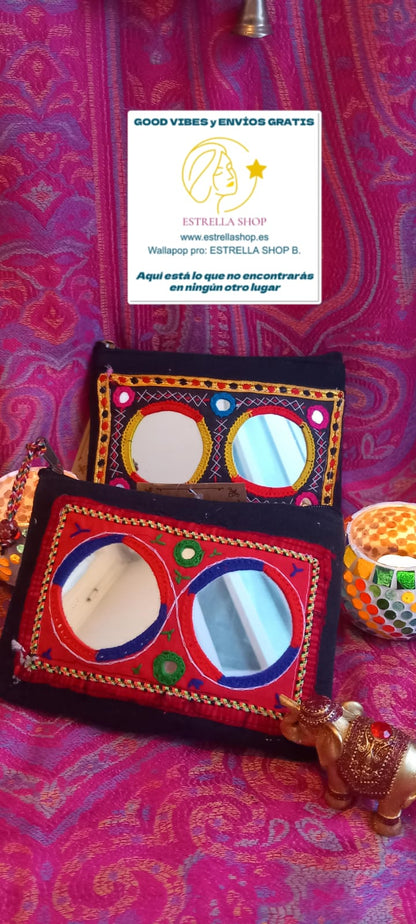 Un complemento pequeño pero lleno de encanto. Es una pieza que fusiona tradición y funcionalidad. Su base oscura crea un contraste perfecto con los vibrantes bordados en hilos de colores y los pequeños espejos que reflejan la esencia artesanal de la cultura Banjara. Ideal para llevar lo esencial con estilo, ya sea como monedero o neceser, y perfecto para combinar con los bolsos de la misma colección.

Características:
- Medida: 20x15 cm