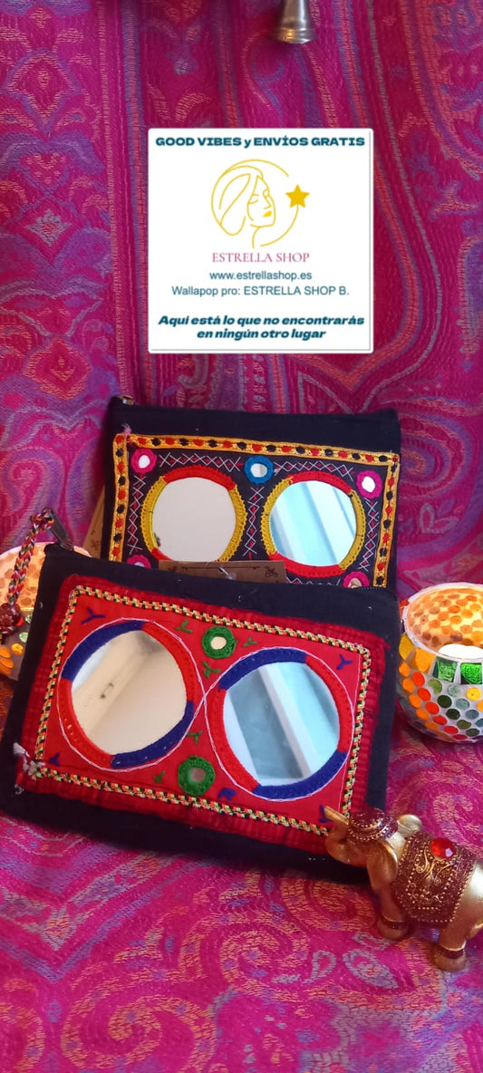 Un complemento pequeño pero lleno de encanto. Es una pieza que fusiona tradición y funcionalidad. Su base oscura crea un contraste perfecto con los vibrantes bordados en hilos de colores y los pequeños espejos que reflejan la esencia artesanal de la cultura Banjara. Ideal para llevar lo esencial con estilo, ya sea como monedero o neceser, y perfecto para combinar con los bolsos de la misma colección.

Características:
- Medida: 20x15 cm