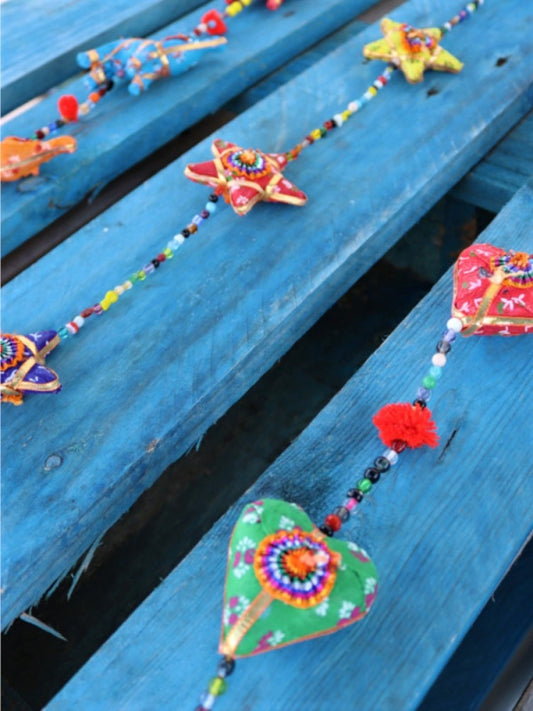 Está elaborado con tela.
Es un tira decorativa donde caen cinco piezas coloridas con figuras de elefantes.
Se intercalan con pequeñas cuentas y pompones, en su extremo tiene una campana.

Medidas aproximadas 100 cm.
ENVÍO GRATIS SIN PEDIDO MÍNIMO.