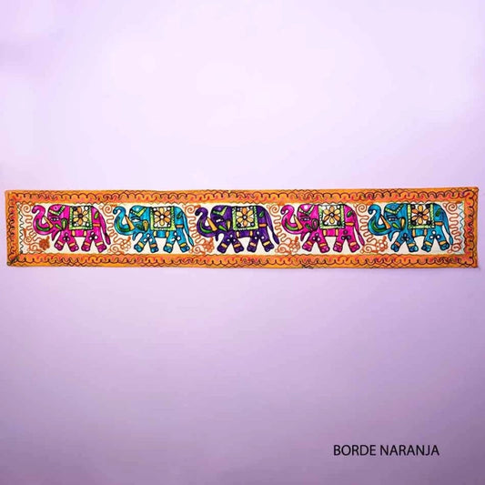 Con unas medidas de 31x180 cm, es perfecto para colgar en paredes, cubrir muebles o incluso utilizar como un elegante camino de mesa. Su diseño presenta cinco elefantes bordados en colores luminosos, creando un efecto visual impactante y alegre. Cada elefante, meticulosamente trabajado, refleja la maestría artesanal de los bordadores, aportando un toque cultural y auténtico a tu decoración.